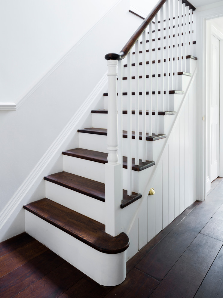 На фото: п-образная лестница среднего размера в викторианском стиле с деревянными ступенями и крашенными деревянными подступенками с