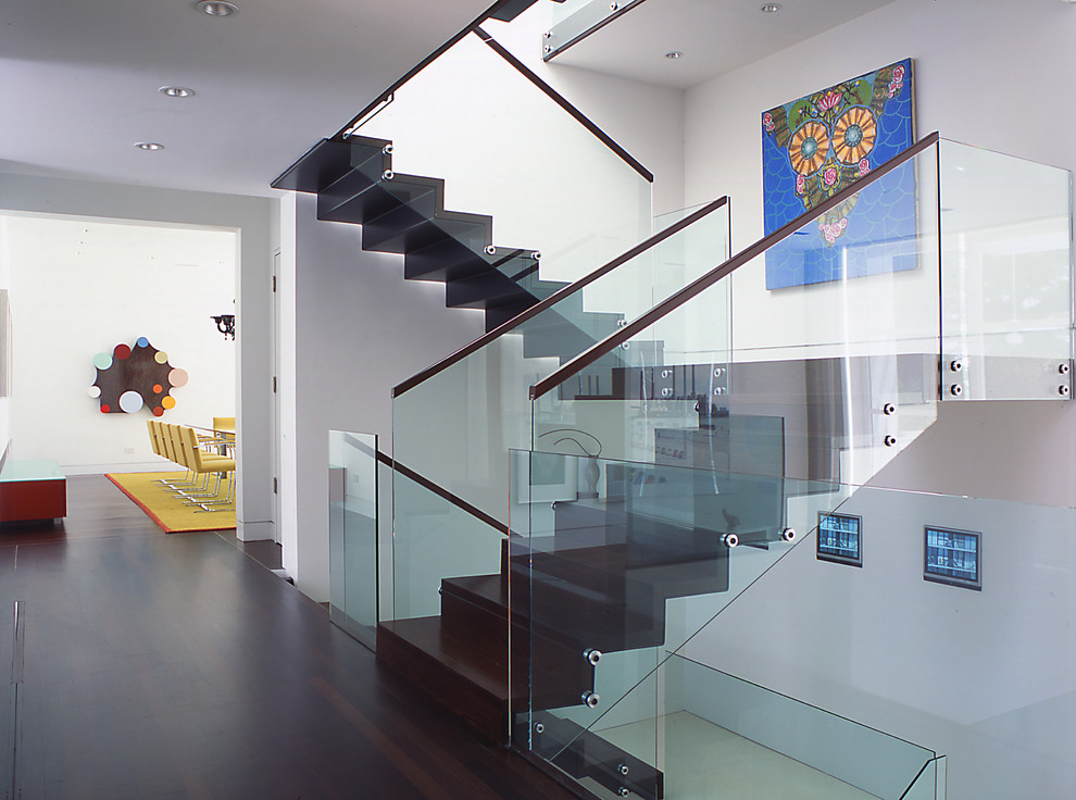Foto de escalera en U actual con escalones de madera, contrahuellas de madera y barandilla de vidrio