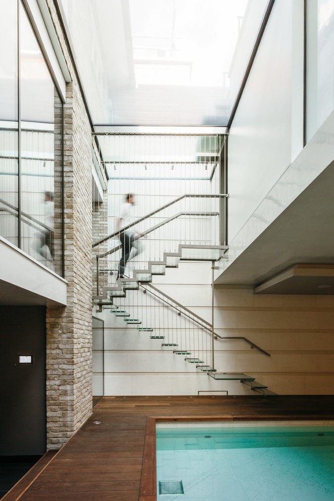 ロンドンにあるラグジュアリーな広いコンテンポラリースタイルのおしゃれなスケルトン階段 (ガラスの蹴込み板) の写真