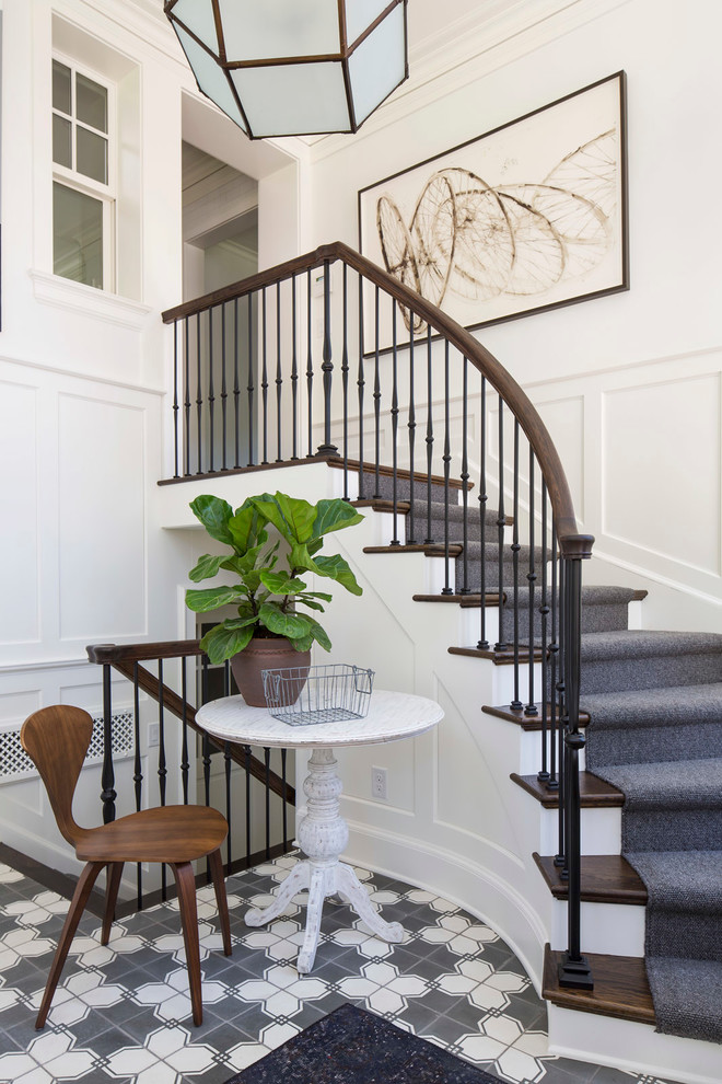 На фото: изогнутая лестница в классическом стиле с деревянными ступенями, крашенными деревянными подступенками и перилами из смешанных материалов с