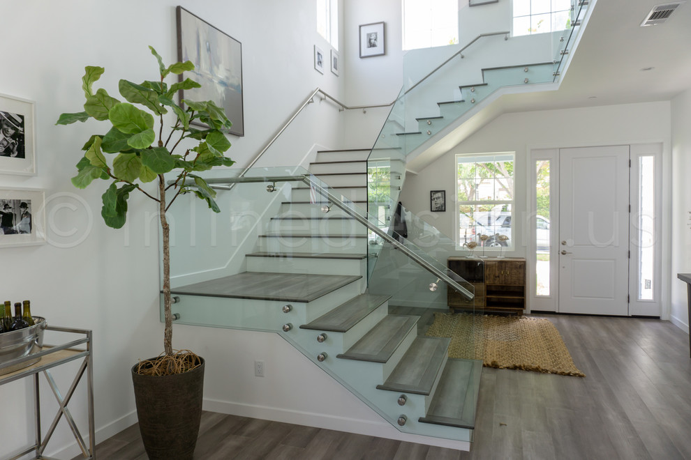 Exemple d'un escalier moderne de taille moyenne avec des contremarches en verre, un garde-corps en verre et des marches en bois.