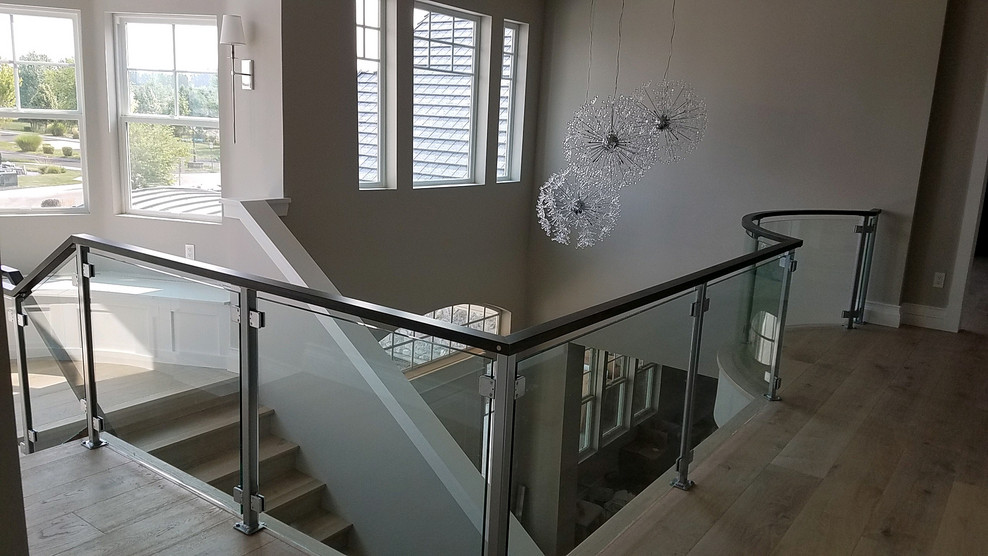 Foto de escalera en U moderna grande con barandilla de vidrio, escalones de madera y contrahuellas de madera