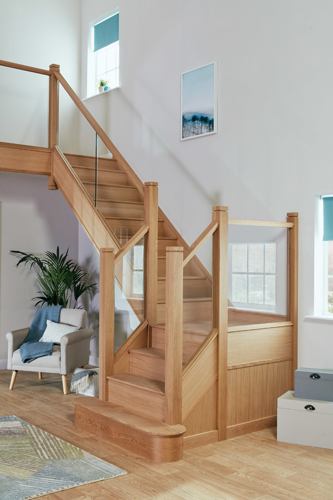 This is an example of a medium sized traditional wood u-shaped glass railing staircase in Manchester with wood risers.
