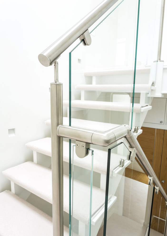 Foto de escalera contemporánea de tamaño medio con escalones enmoquetados y barandilla de metal