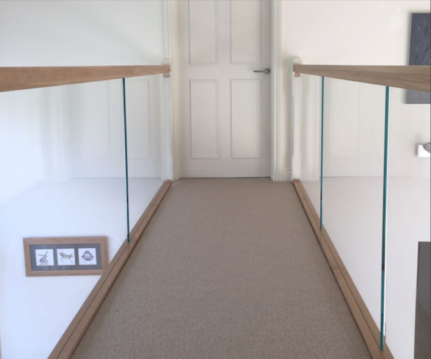 Carpeted l-shaped glass railing staircase photo in Cheshire with carpeted risers
