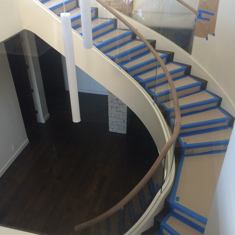 Réalisation d'un très grand escalier courbe minimaliste avec des marches en bois et des contremarches en bois.