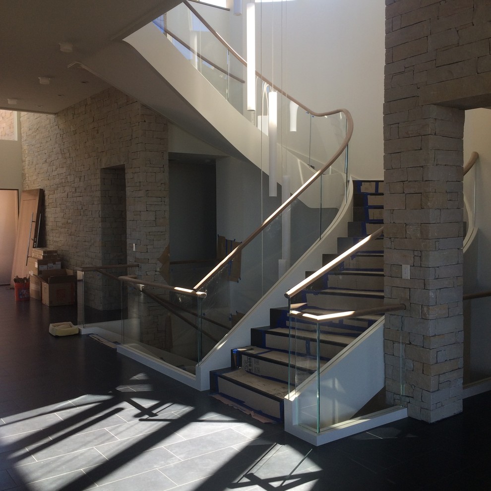 Idée de décoration pour un très grand escalier courbe minimaliste avec des marches en bois et des contremarches en bois.