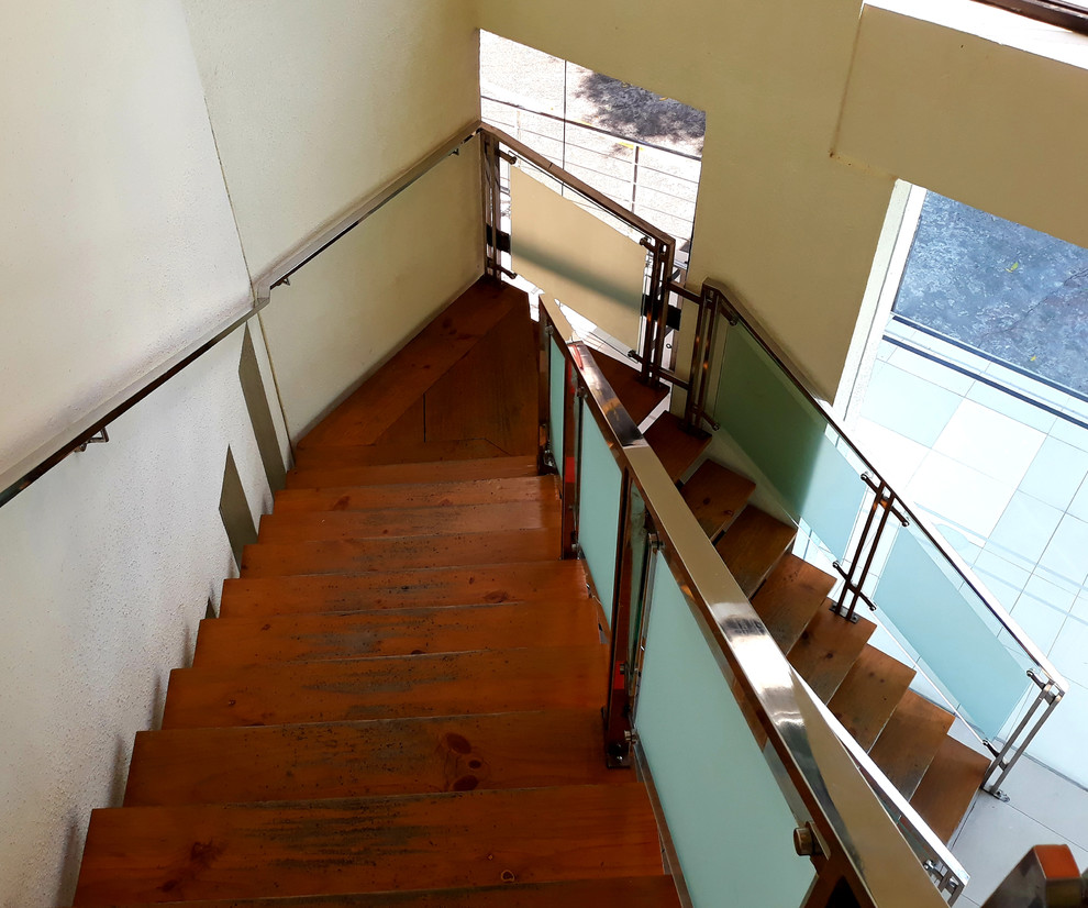 Diseño de escalera en L contemporánea sin contrahuella con barandilla de vidrio y escalones de madera
