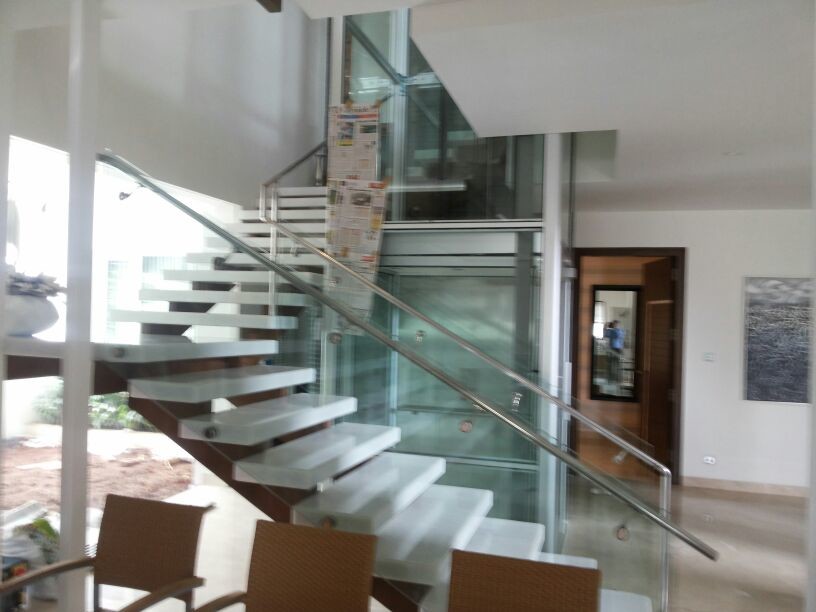 Diseño de escalera suspendida actual de tamaño medio con escalones de vidrio y contrahuellas de hormigón
