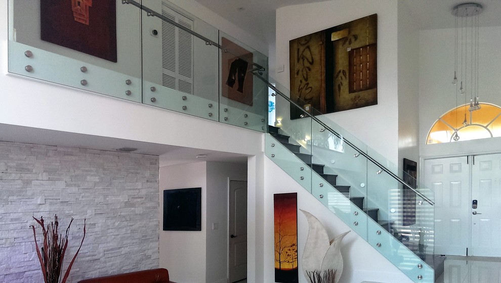 Cette image montre un escalier droit minimaliste de taille moyenne avec des marches en bois, des contremarches en bois et un garde-corps en verre.