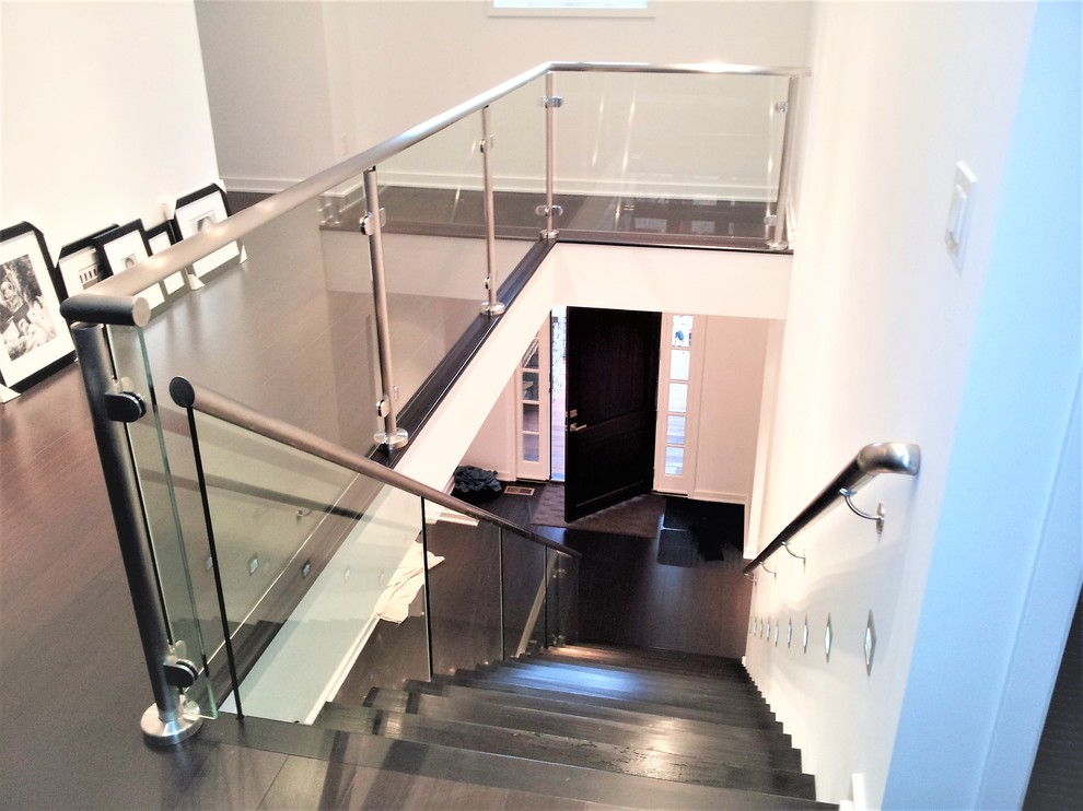 Ejemplo de escalera suspendida moderna grande con escalones de madera pintada y barandilla de vidrio