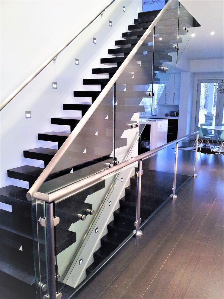 Diseño de escalera suspendida moderna grande con escalones de madera pintada y barandilla de vidrio