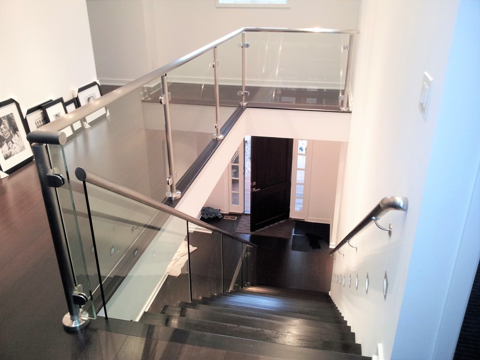 Imagen de escalera suspendida moderna grande con escalones de madera pintada y barandilla de vidrio
