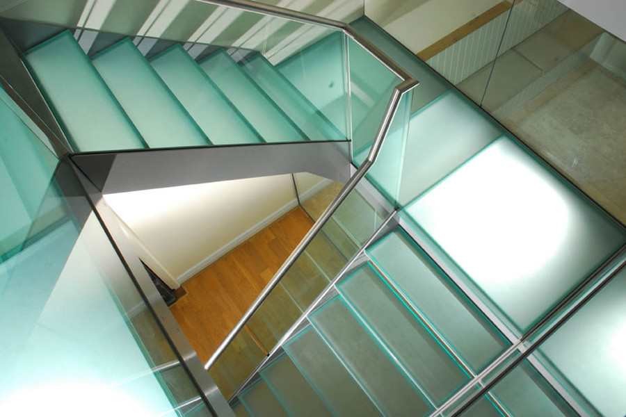Cette photo montre un grand escalier sans contremarche tendance en U avec des marches en verre et un garde-corps en verre.
