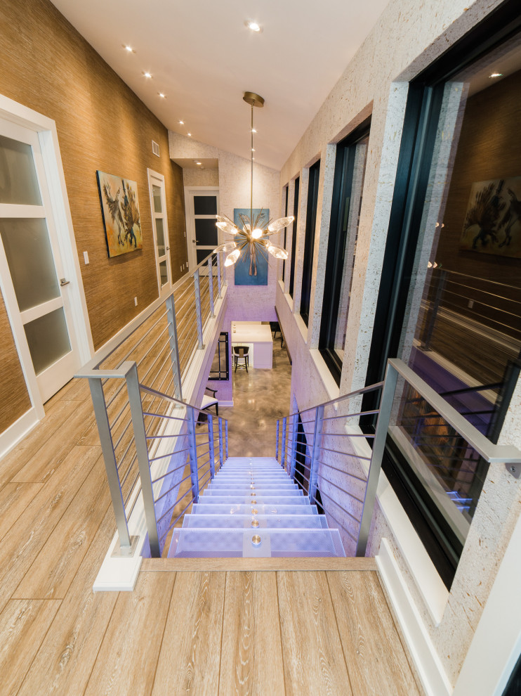 Idée de décoration pour un grand escalier sans contremarche flottant minimaliste avec des marches en verre, un garde-corps en métal et du papier peint.
