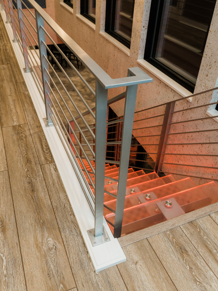 Foto de escalera suspendida moderna grande sin contrahuella con escalones de vidrio, barandilla de metal y papel pintado