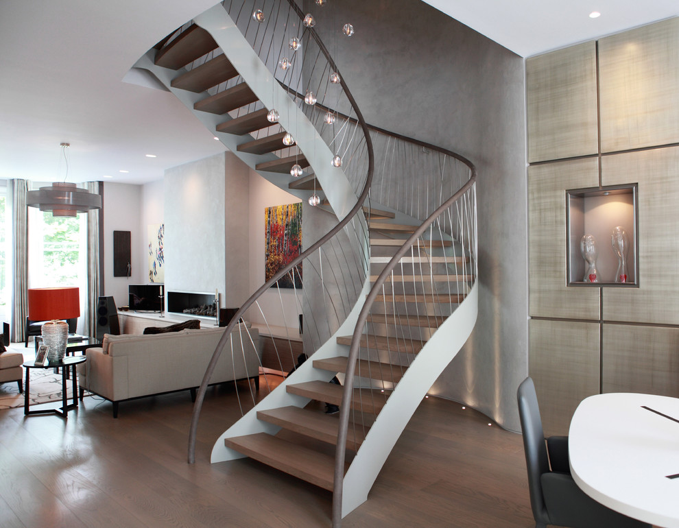 This is an example of a medium sized contemporary wood curved staircase in London with open risers and feature lighting.