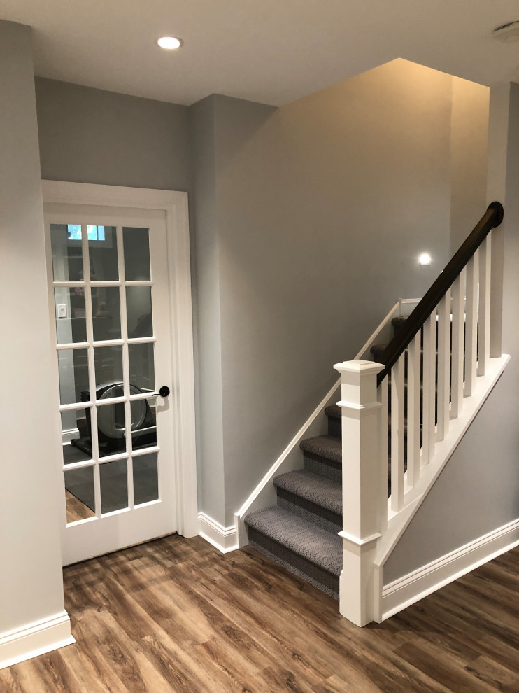 Idée de décoration pour un grand escalier minimaliste en L avec des marches en moquette, des contremarches en moquette et un garde-corps en bois.