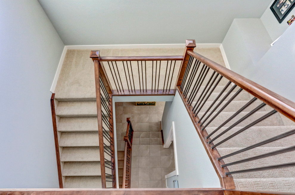 Large classic carpeted u-shaped staircase in Calgary with carpeted risers.