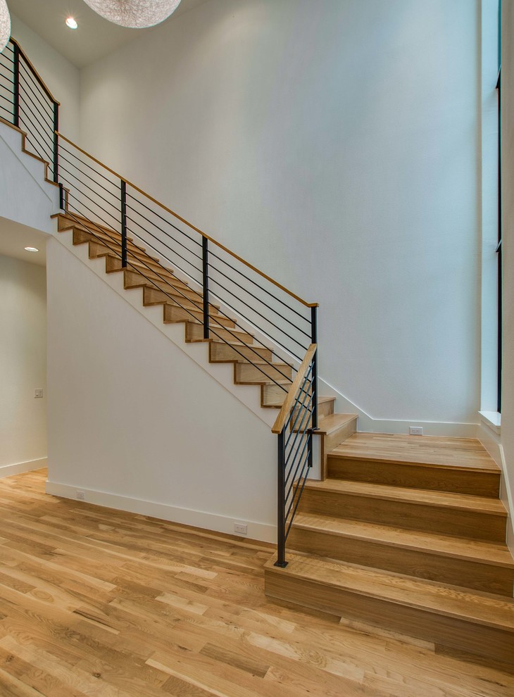 Imagen de escalera en L minimalista con escalones de madera, contrahuellas de madera y barandilla de metal