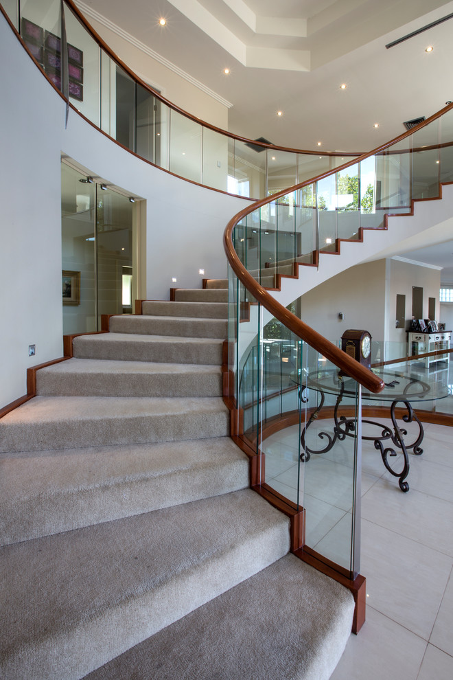 Idées déco pour un grand escalier courbe contemporain avec des marches en moquette, des contremarches en moquette et un garde-corps en verre.
