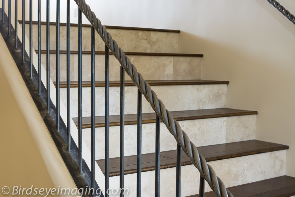 На фото: огромная п-образная лестница в стиле неоклассика (современная классика) с деревянными ступенями и подступенками из плитки