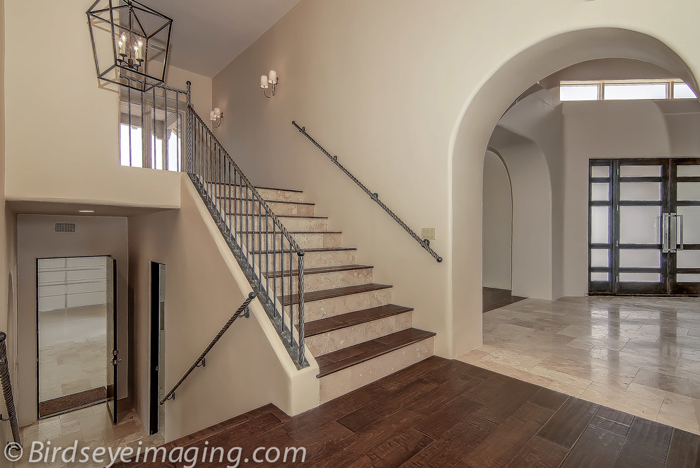 На фото: огромная п-образная лестница в стиле неоклассика (современная классика) с деревянными ступенями и подступенками из плитки с