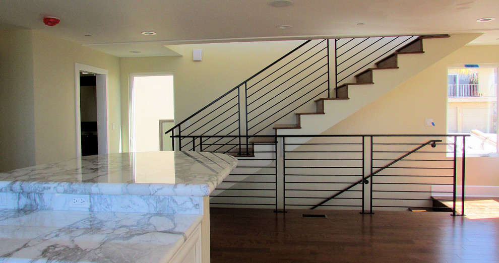 Ejemplo de escalera recta contemporánea grande con escalones de madera, contrahuellas de madera y barandilla de metal