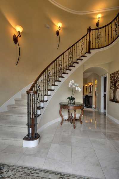 Пример оригинального дизайна: огромная изогнутая лестница в классическом стиле с ковровыми подступенками