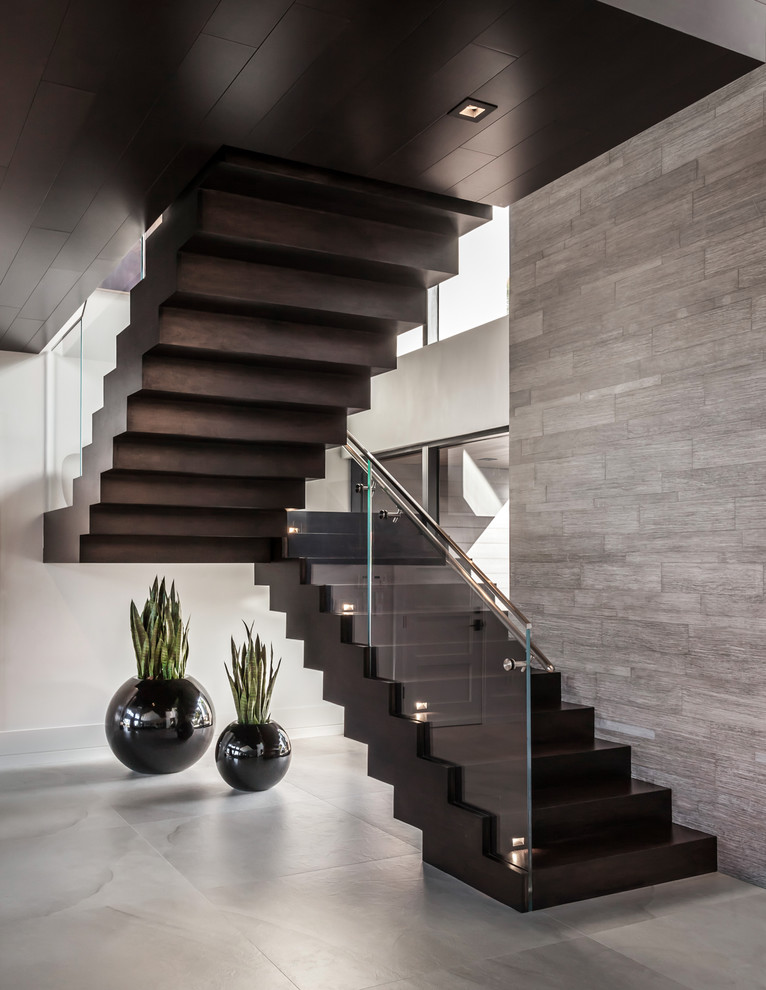 Inspiration pour un grand escalier design en U avec des marches en bois, des contremarches en bois, un garde-corps en verre, palier et éclairage.