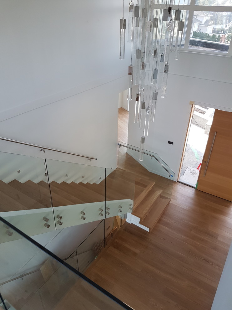 Foto de escalera suspendida minimalista grande sin contrahuella con escalones de madera y barandilla de vidrio