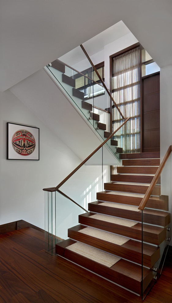 На фото: большая п-образная деревянная лестница в современном стиле с деревянными ступенями и стеклянными перилами с