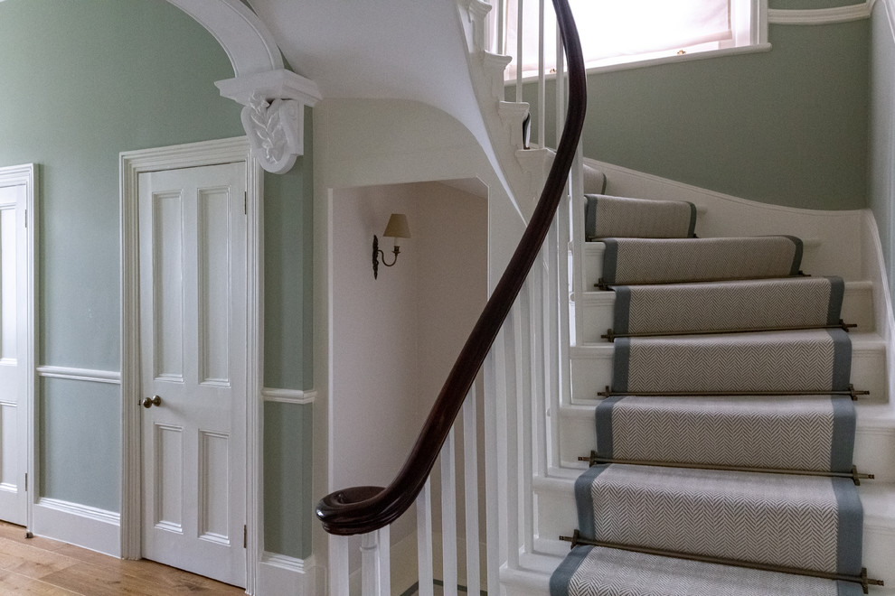Foto de escalera curva clásica con escalones enmoquetados, contrahuellas de madera y barandilla de madera