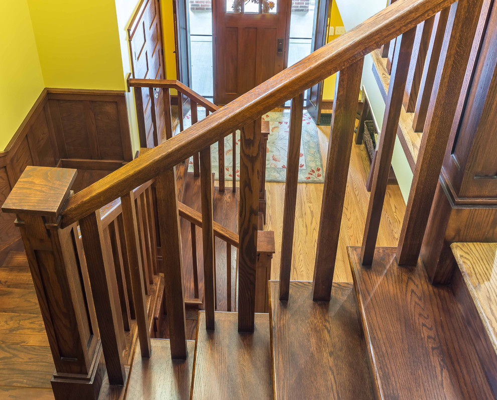 На фото: п-образная деревянная лестница среднего размера в стиле кантри с деревянными ступенями, деревянными перилами и панелями на стенах с