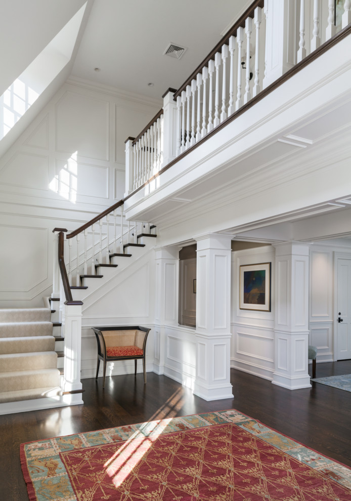 На фото: огромная угловая лестница в классическом стиле с ступенями с ковровым покрытием и ковровыми подступенками