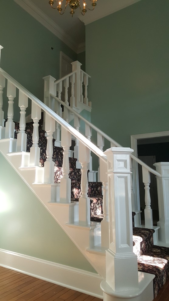 Пример оригинального дизайна: большая угловая лестница в викторианском стиле с ступенями с ковровым покрытием и ковровыми подступенками