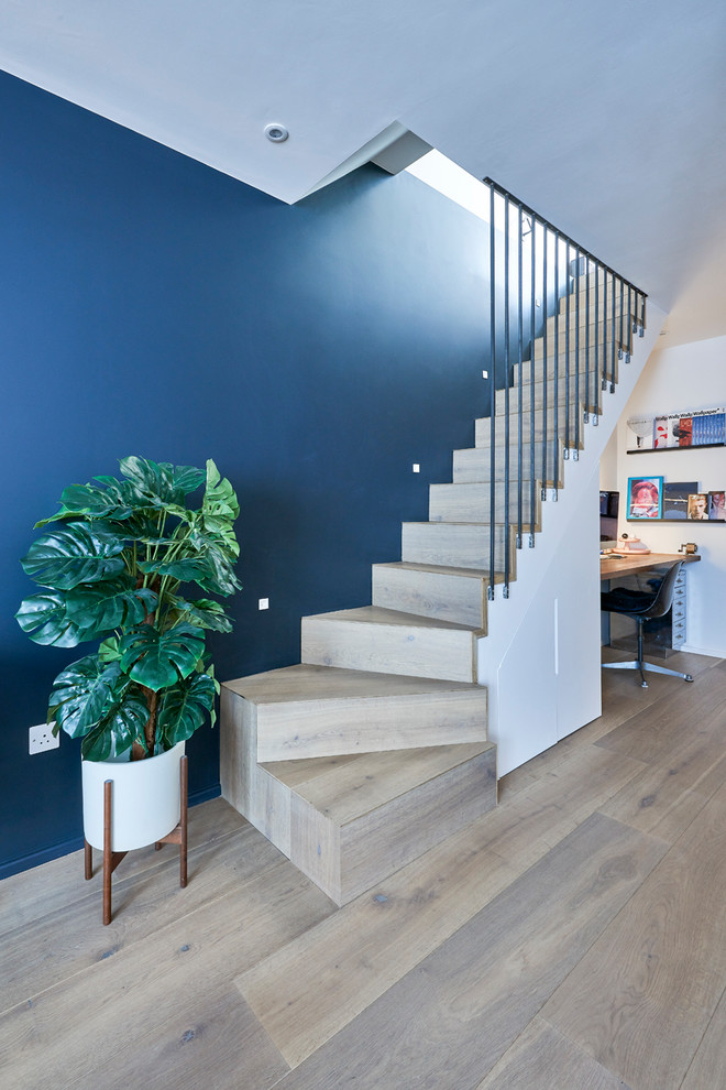 Photo of a contemporary wood l-shaped metal railing staircase in London with wood risers and a feature wall.