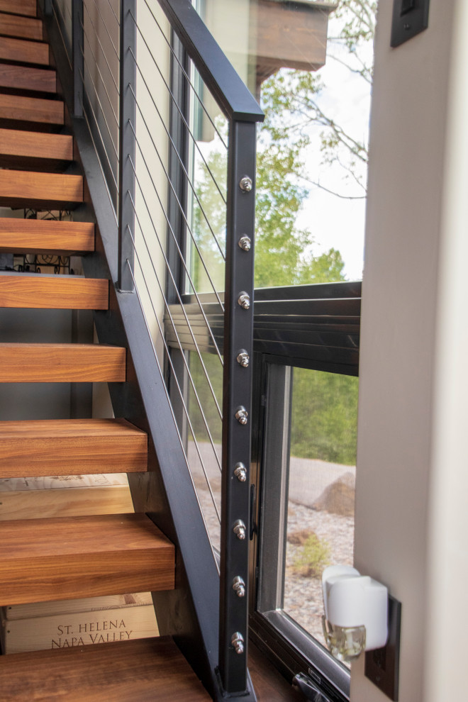 Photo of a large modern wood straight metal railing staircase in Other with metal risers.