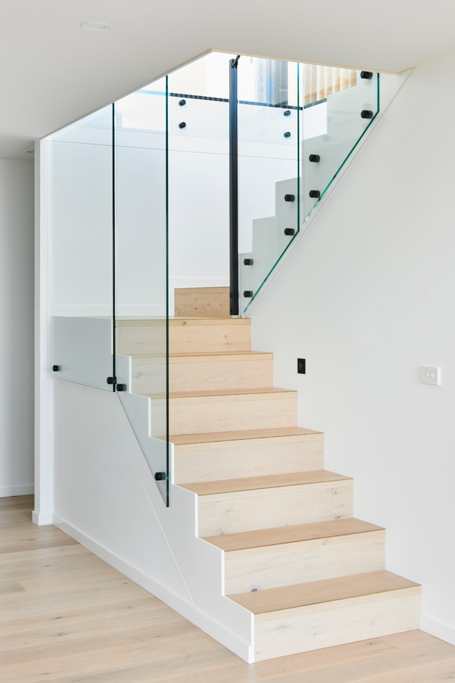 Cette image montre un escalier design en U de taille moyenne avec des marches en bois et un garde-corps en métal.