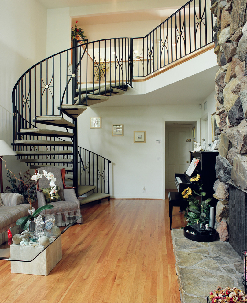 На фото: большая винтовая лестница в классическом стиле с металлическими ступенями без подступенок