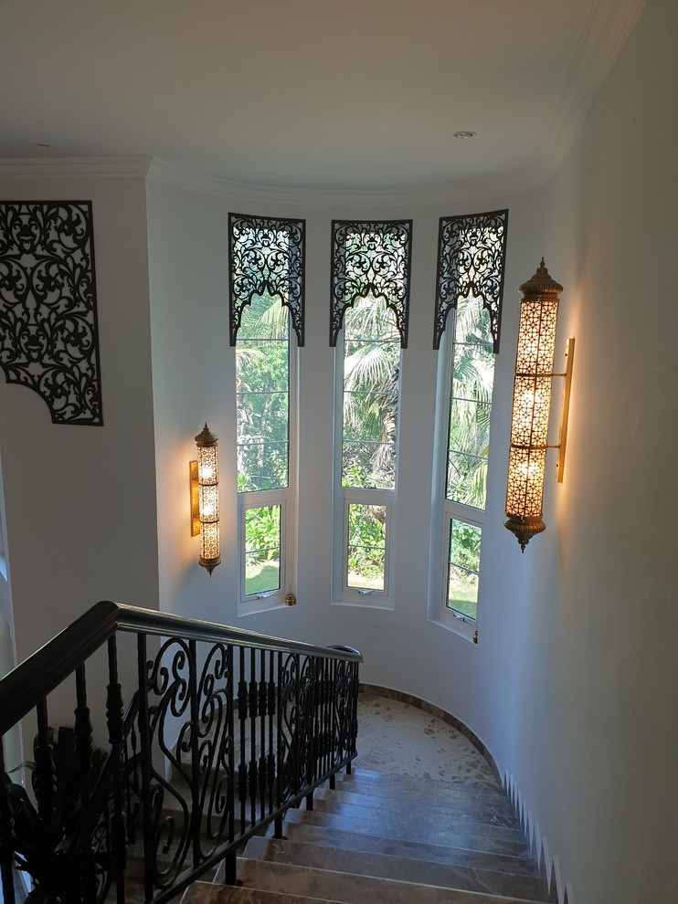 Пример оригинального дизайна: большая изогнутая лестница в стиле фьюжн с деревянными перилами