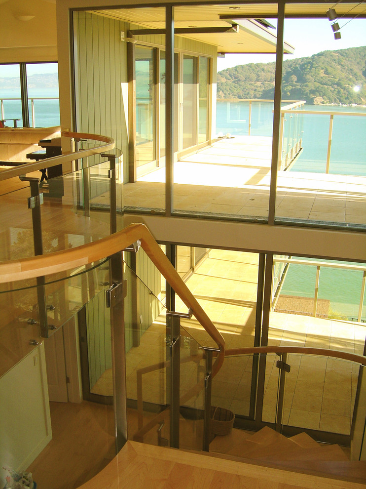 Стильный дизайн: изогнутая лестница в современном стиле с деревянными ступенями и деревянными перилами - последний тренд