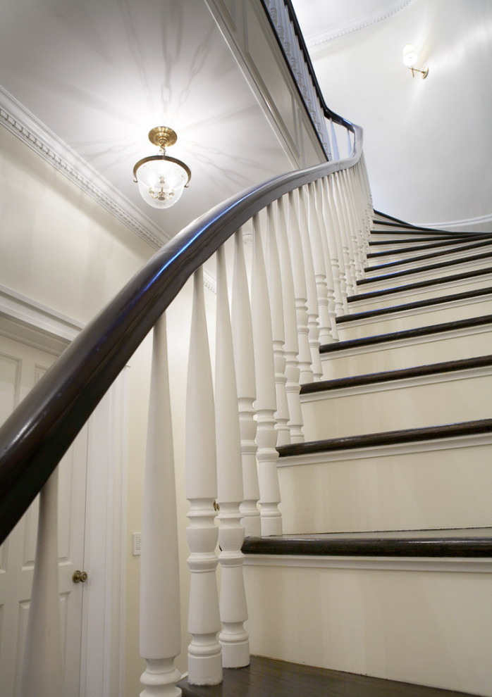 Ejemplo de escalera curva tradicional renovada grande con escalones de madera, contrahuellas de madera y barandilla de madera