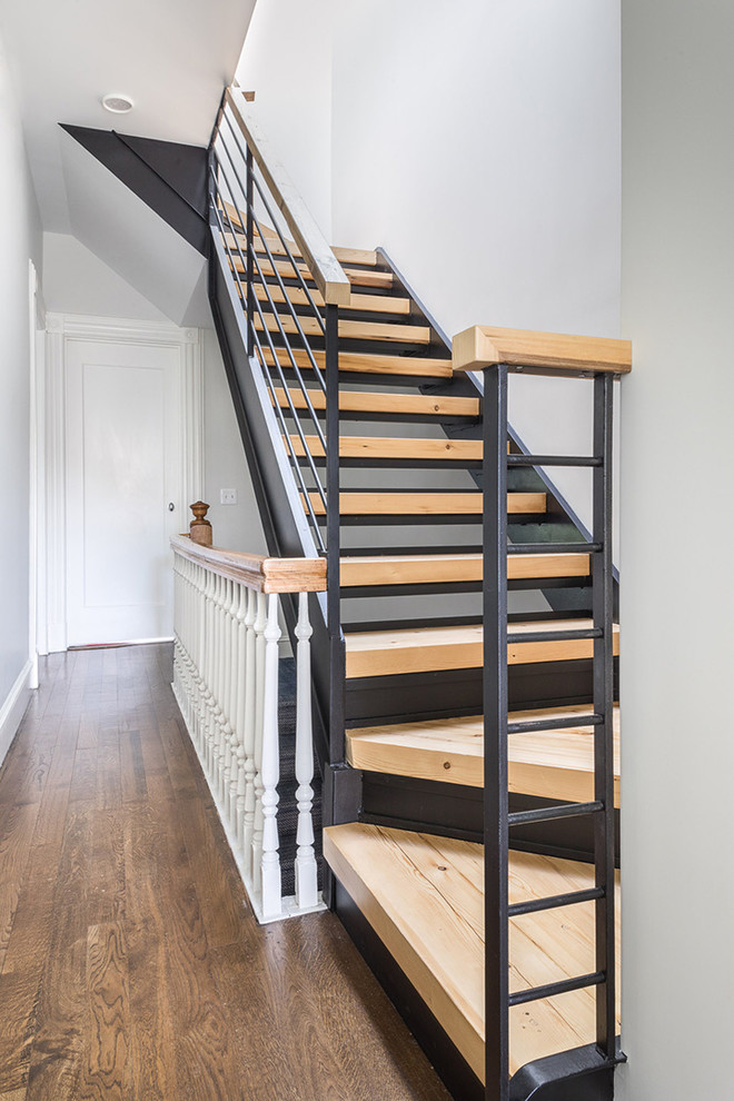 Cette image montre un petit escalier minimaliste en U avec des marches en bois, des contremarches en métal et un garde-corps en bois.