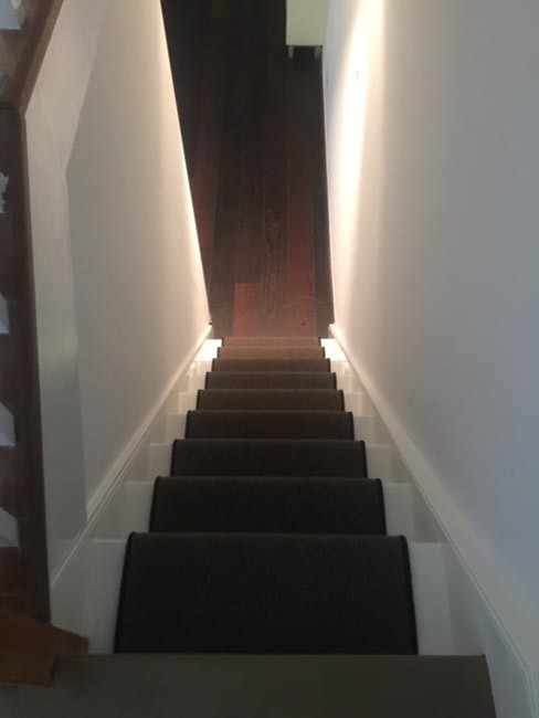 На фото: п-образная лестница в современном стиле с ступенями с ковровым покрытием, ковровыми подступенками и деревянными перилами с