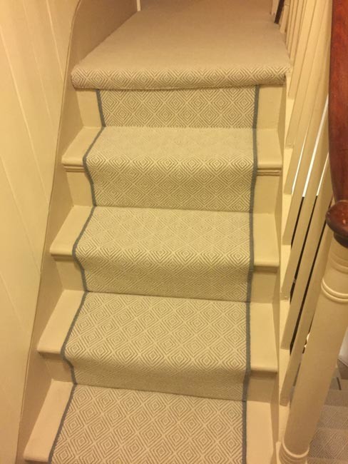 ロンドンにあるコンテンポラリースタイルのおしゃれな折り返し階段 (カーペット張りの蹴込み板、木材の手すり) の写真