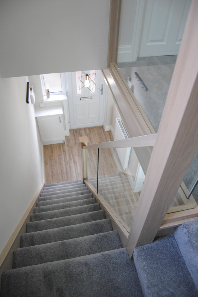 Ejemplo de escalera recta contemporánea pequeña con escalones enmoquetados, contrahuellas enmoquetadas y barandilla de vidrio
