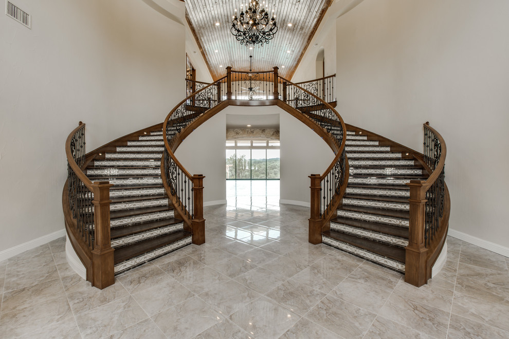 Свежая идея для дизайна: огромная изогнутая лестница в стиле неоклассика (современная классика) с деревянными ступенями и подступенками из плитки - отличное фото интерьера
