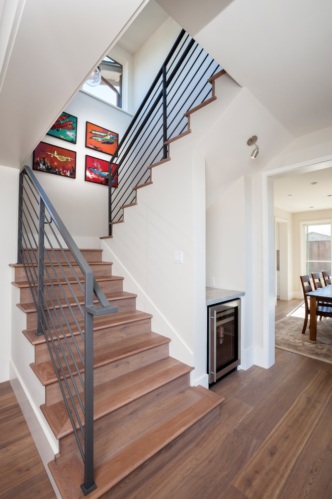 This is an example of a traditional wood u-shaped metal railing staircase in San Francisco with wood risers and feature lighting.