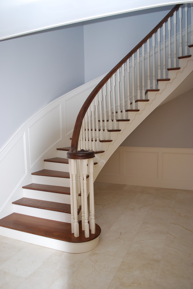 Пример оригинального дизайна: большая изогнутая деревянная лестница в классическом стиле с деревянными ступенями